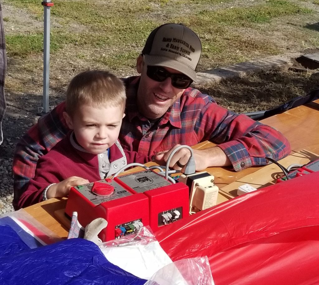 Young boy and father at controls of large scale train.